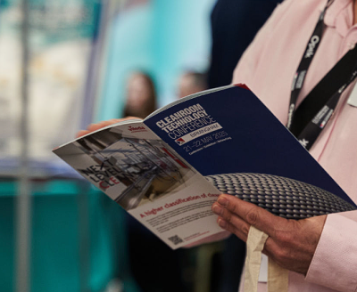 An attendee to the Cleanroom Technology Conference browses through a booklet about the conference held in Birmingham from May 21-22 2025.