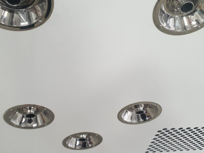 Interior detail of PBSC air shower showing polished stainless steel high velocity air supply nozzles mounted on wall panel with perforated return air grille