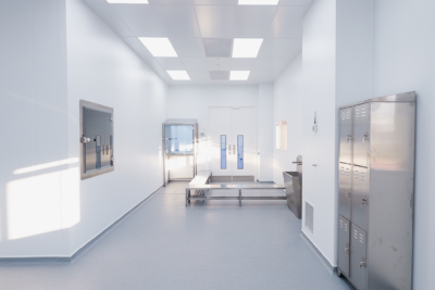 Pharmaceutical cleanroom interior showing a wall-mounted transfer hatch, freestanding pass-through unit, double-door airlock and stainless steel lockers and bench